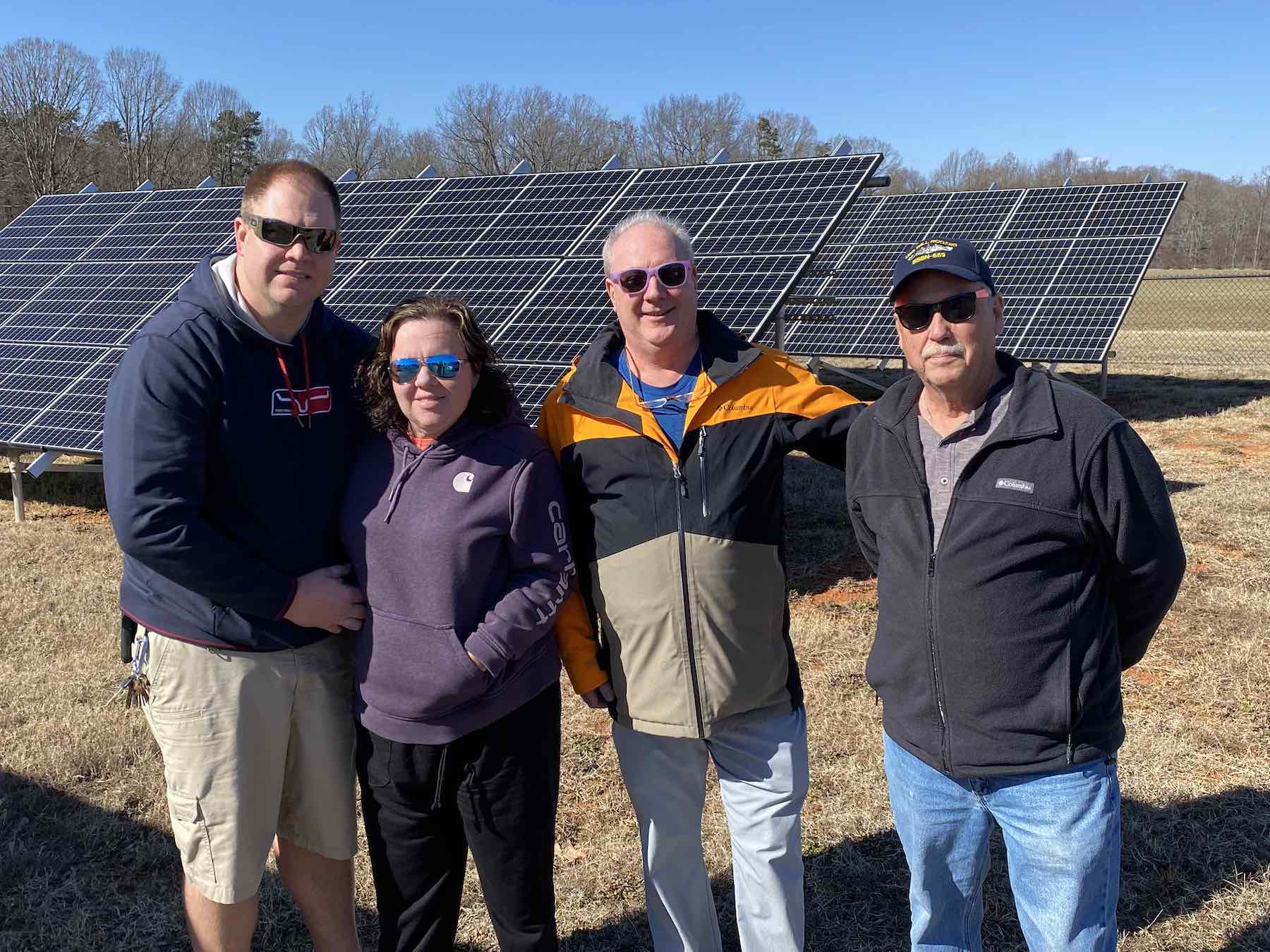 Brad Johnson, chair of the Board of Trustees; Chrissy Johnson, elder; Dan Johnson, grant applicant; and Rick Hensdale, trustee, stand in front of the Solar Array, which is visible from the church, recreation building, and thrift store.